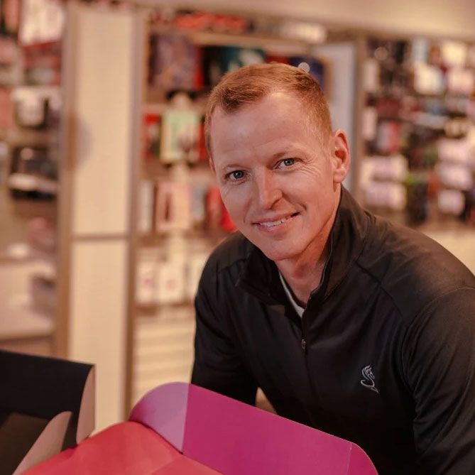 A man in a black jacket is sitting in front of a pink box