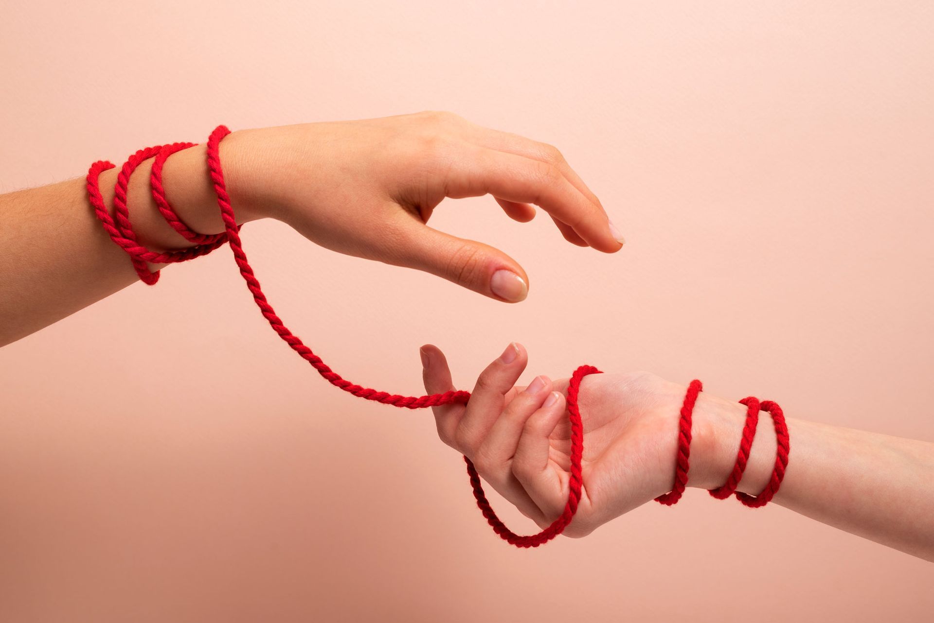 A couple of hands tied together with a red string.
