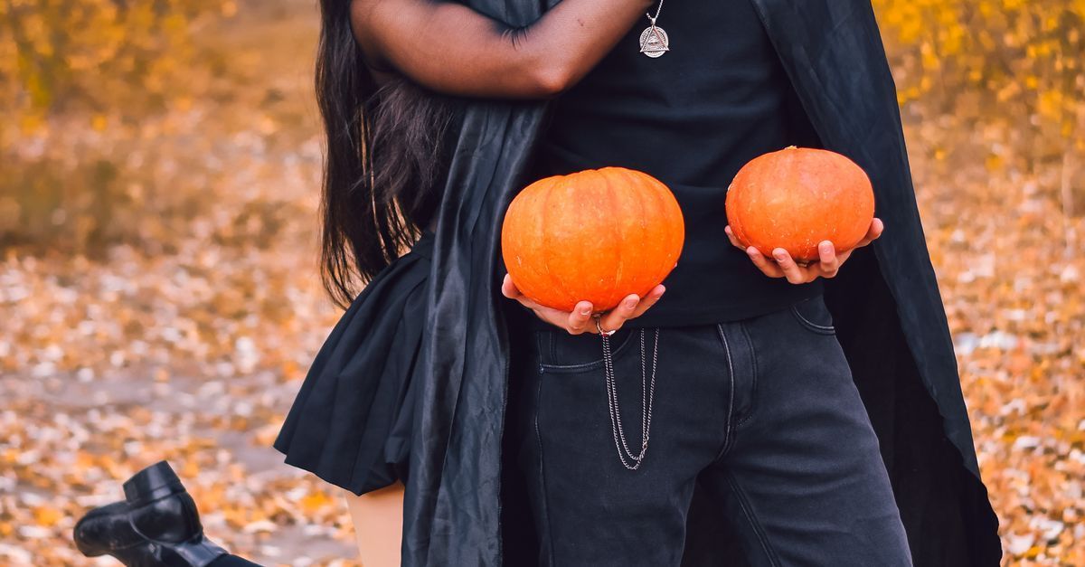 Adult couple in stylish Halloween costumes in a moody upscale bedroom