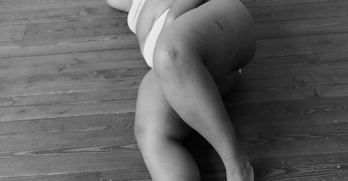 Confident plus size woman in elegant lingerie in a softly lit bedroom