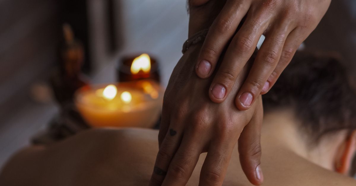 Adult couple with a body massage candle glowing in a warm upscale bedroom