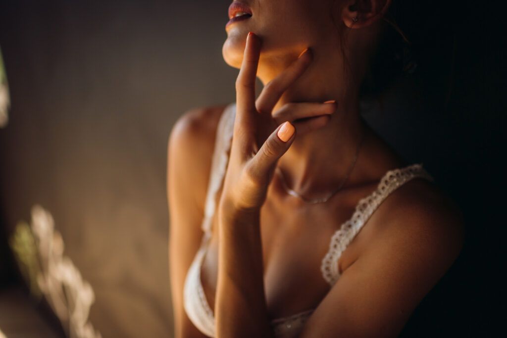 A woman in a white bra is holding her hand to her face.