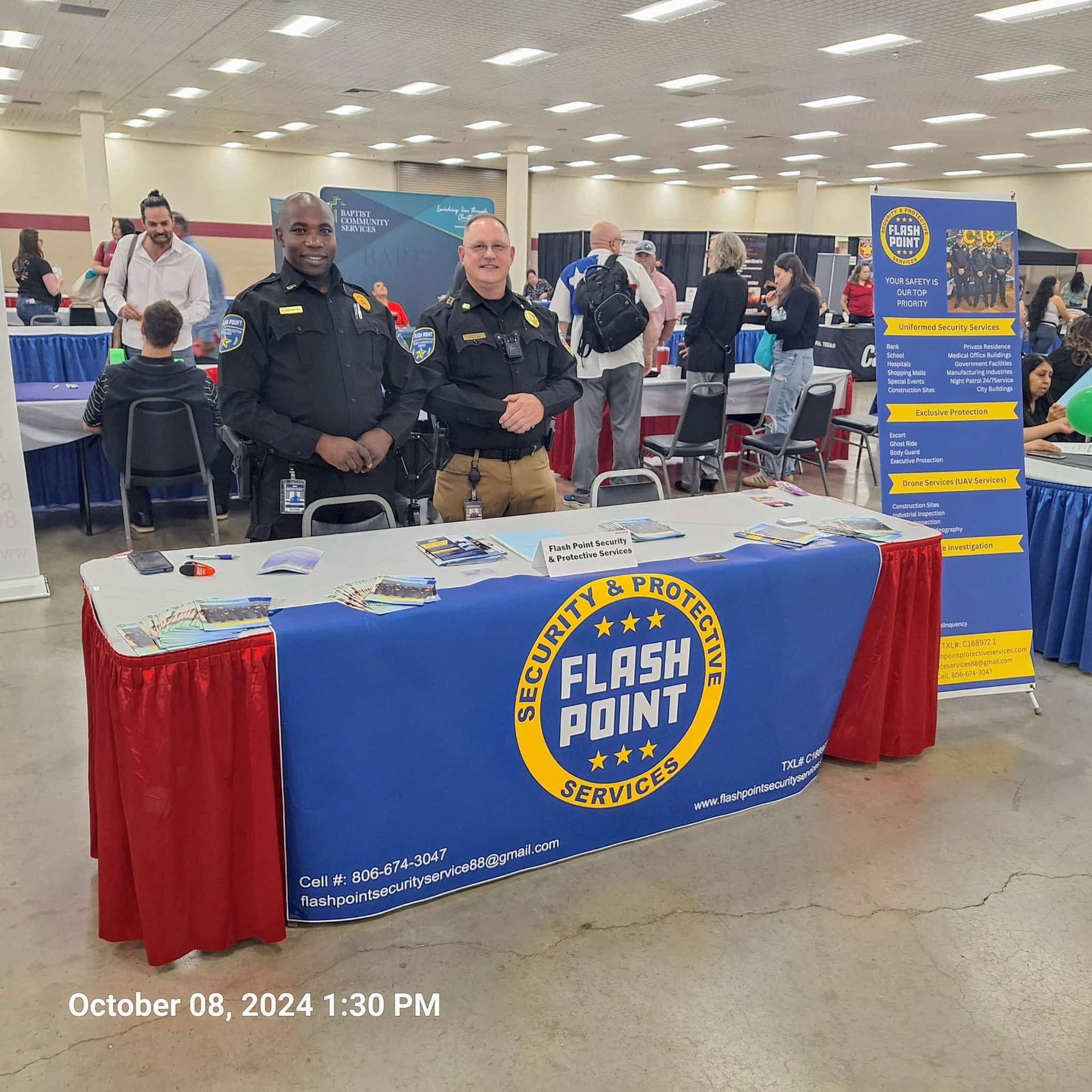 Fire department booth at a community event with two uniformed officers and a blue table display