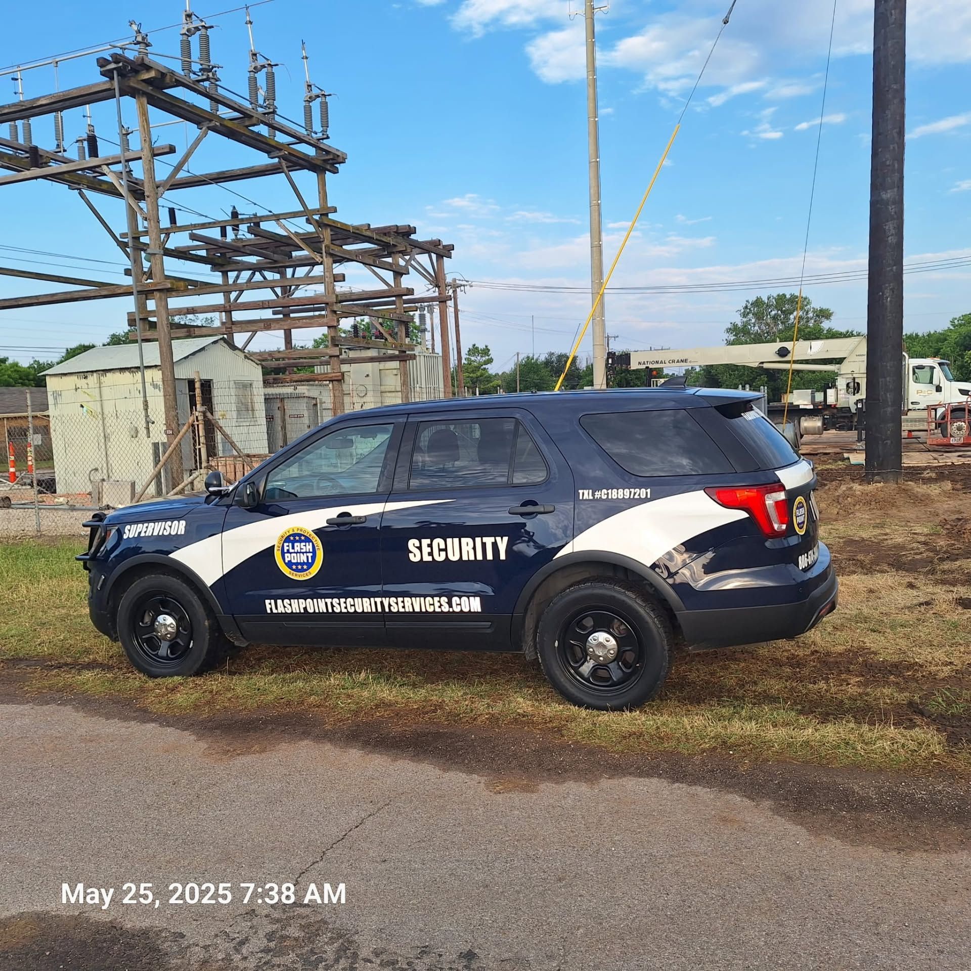 Black security SUV parked by an industrial structure under a blue sky.