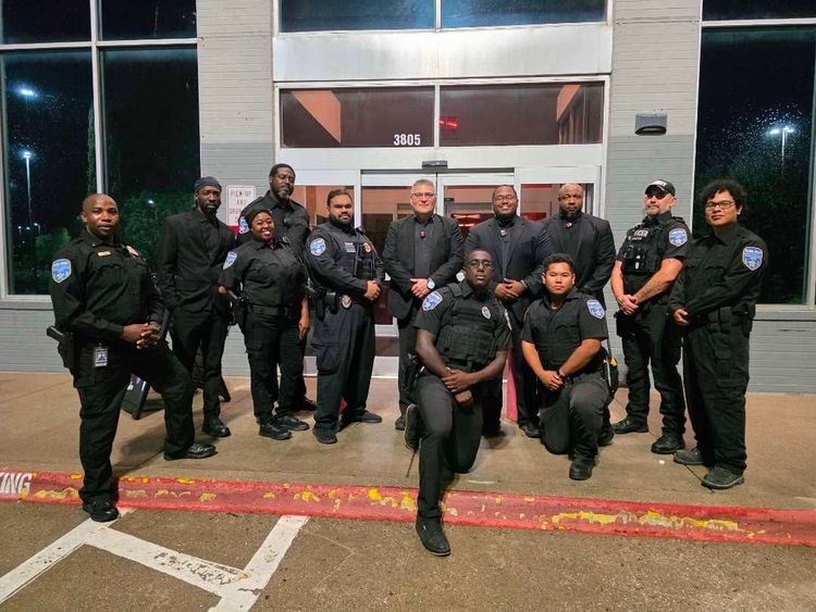 Group of uniformed security officers posing outside a building at night