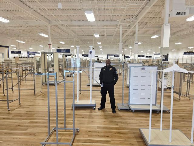 Empty retail store interior with clothing racks and a person standing in the center aisle