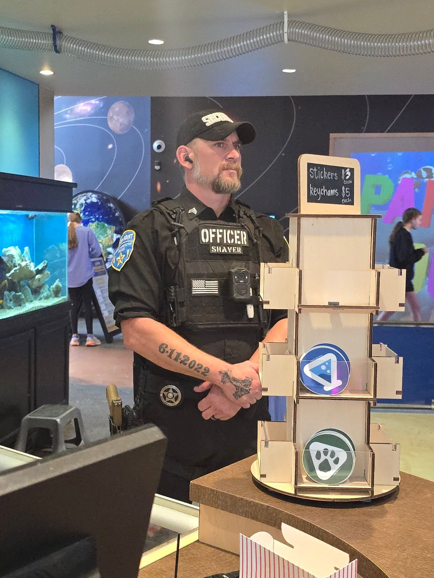 Security officer beside a stacked cardboard display at an indoor event booth