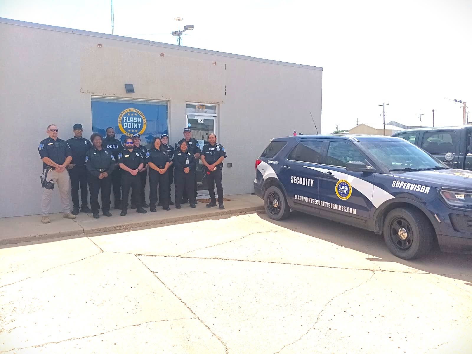 Police officers pose beside a patrol car outside a building with a police emblem.