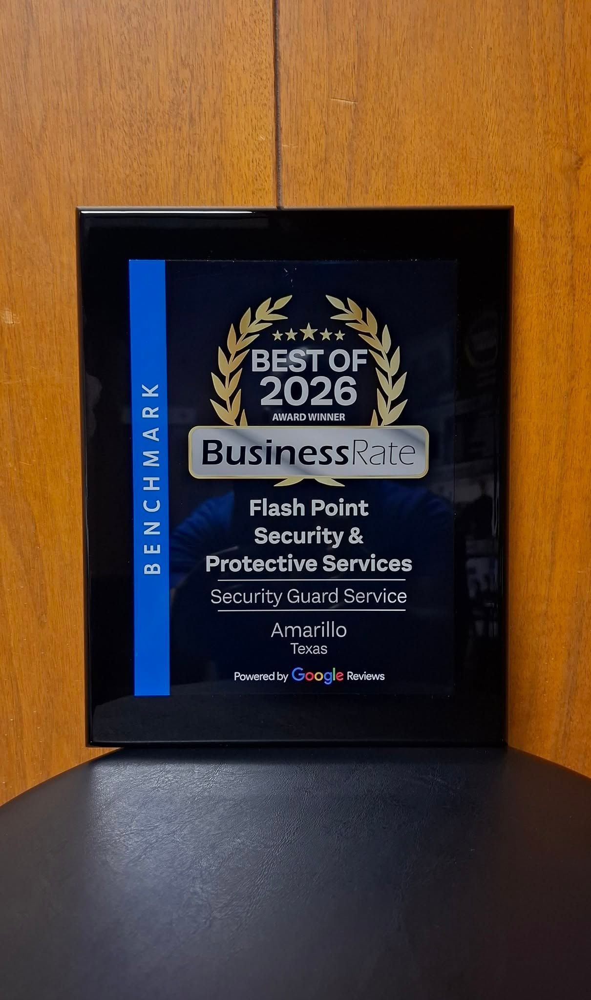 Framed black award plaque with blue stripe, reading “Best of 2026” and “Business #1” on a wooden surface