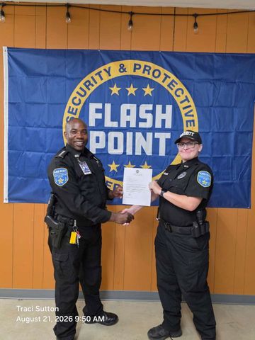 Three people pose at a police backdrop, with two officers flanking a casually dressed person.