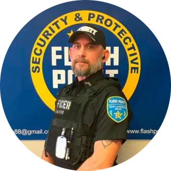 Security guard in black uniform standing before a blue Flash Point Security & Protective logo.