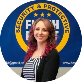 Woman standing before a blue-and-gold Security & Protective logo, smiling at the camera.