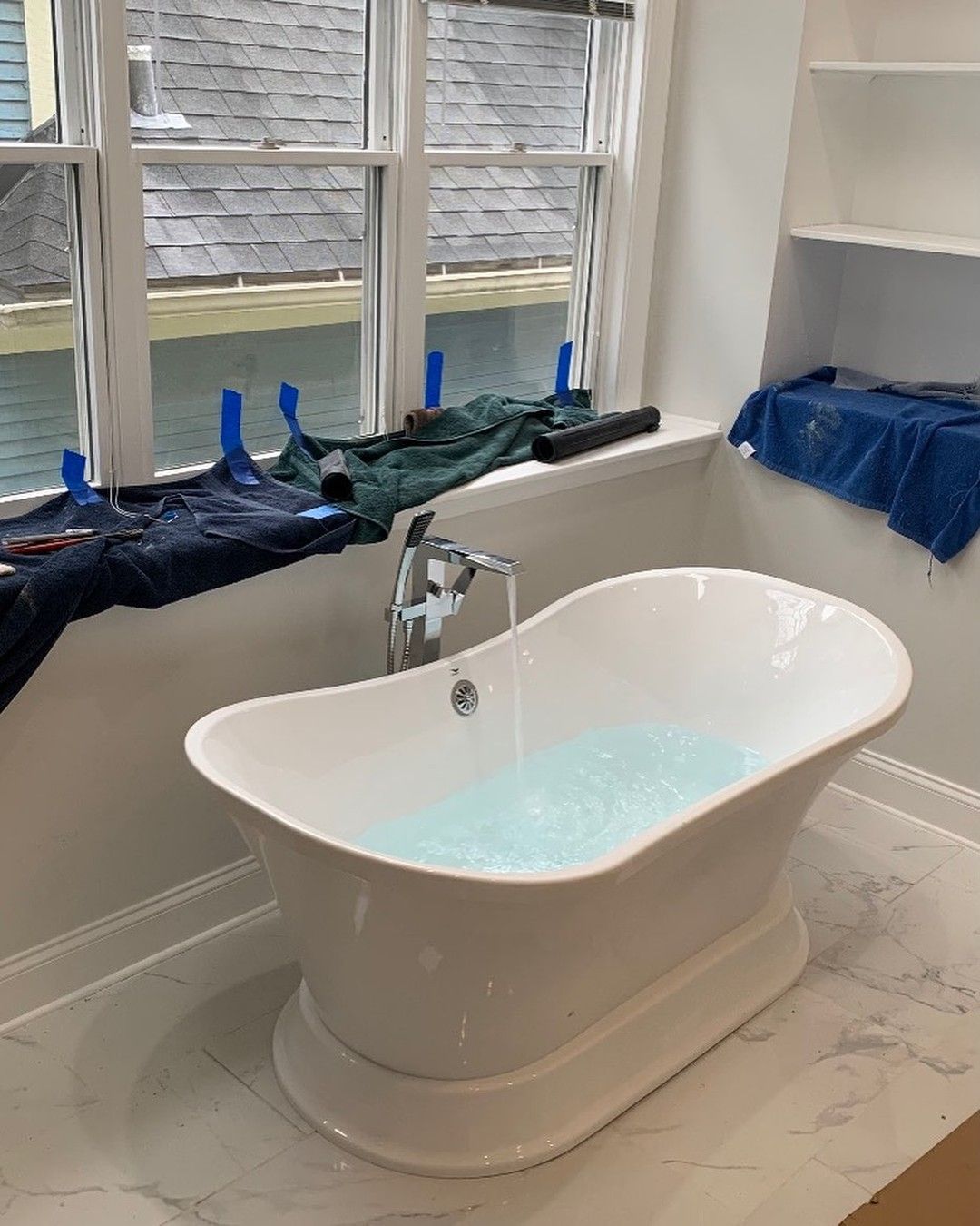 Bathtub and shower faucet repair with modern tub installation in residential bathroom
