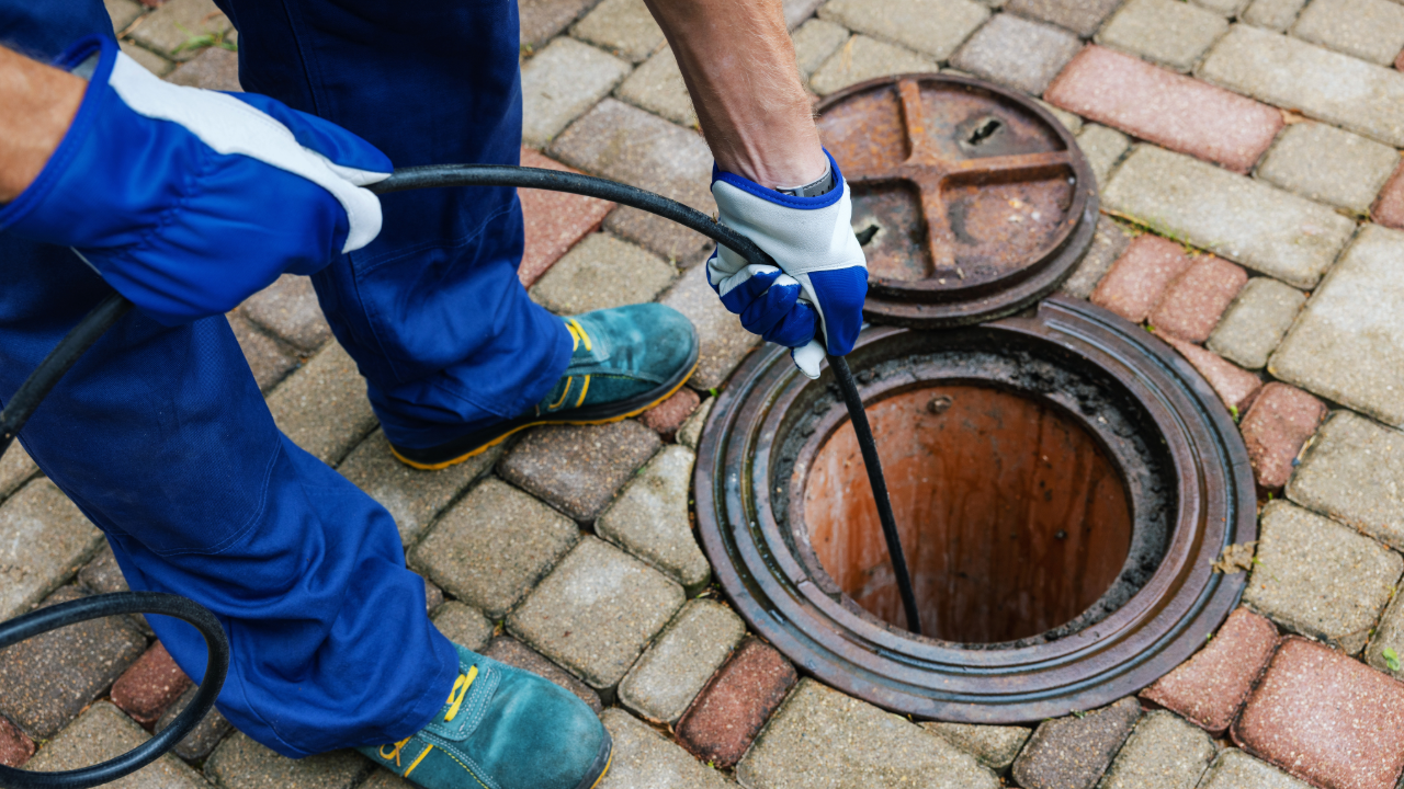 Drain cleaning plumber using auger for clogged sewer line repair