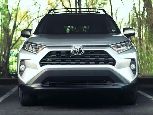Silver Toyota RAV4 SUV, parked in front of trees.