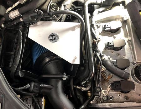 An AFE cold air intake system installed in a car engine bay, featuring a blue air filter and metal heat shield.