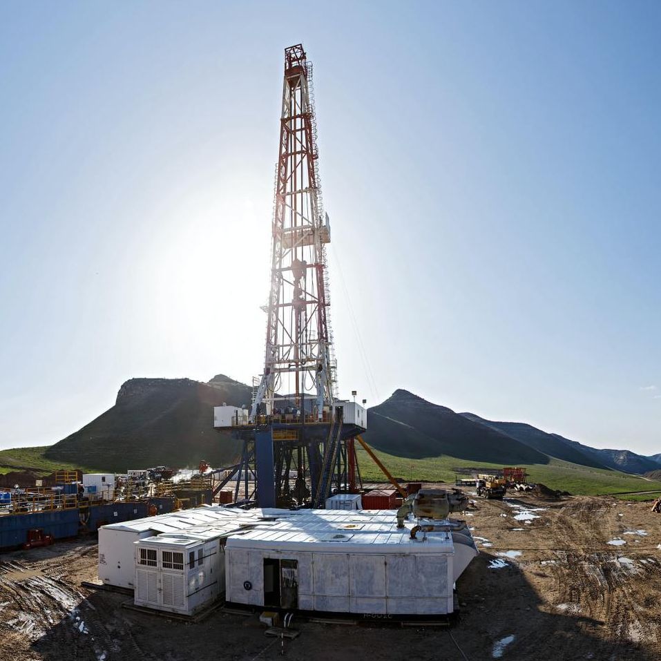 a large crane is in the middle of a field with mountains in the background