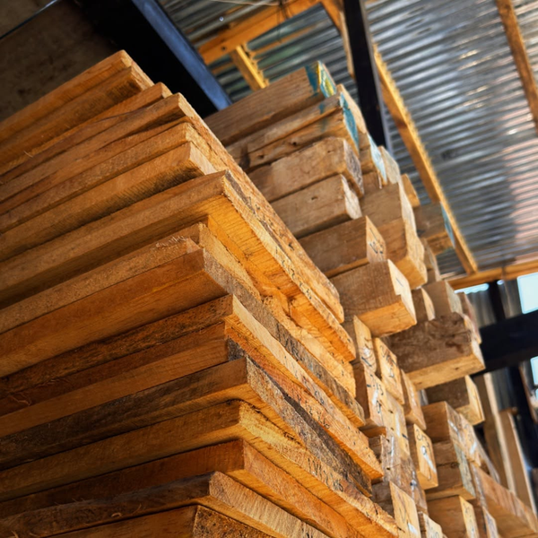 Tablones de madera apilados en estanterías industriales dentro de un almacén.
