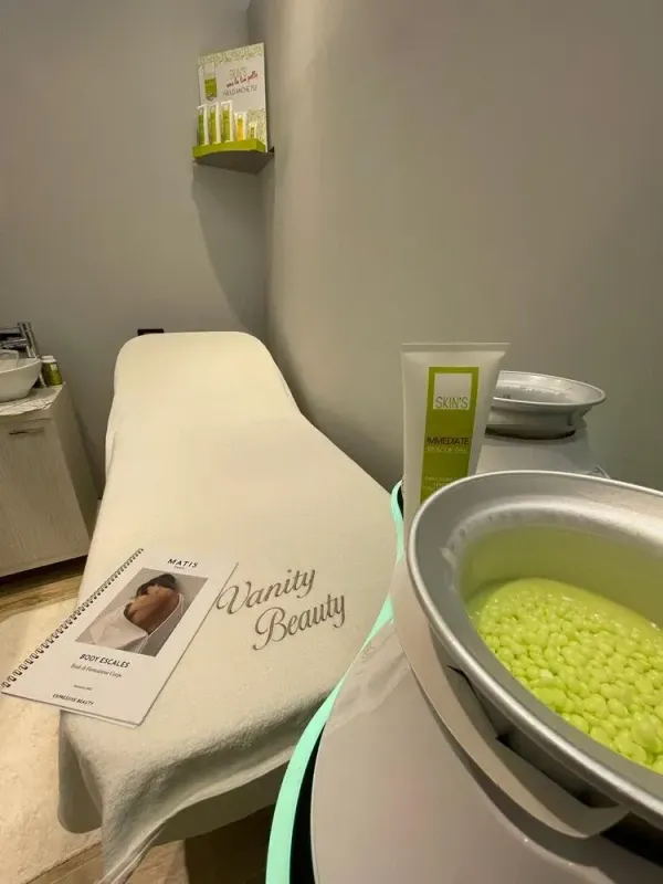 Sala trattamenti spa con lettino da massaggio, asciugamani arrotolati e ciotola di perline verdi per il viso.