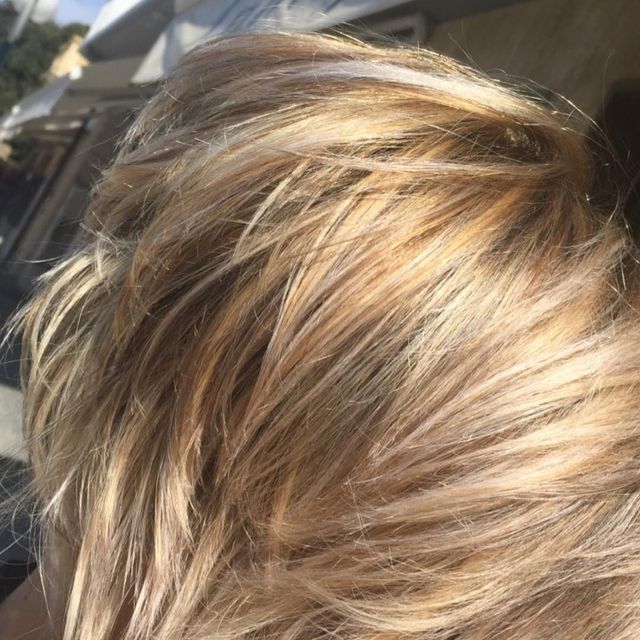 Primo piano di capelli biondi illuminati dal sole con morbidi riflessi e onde