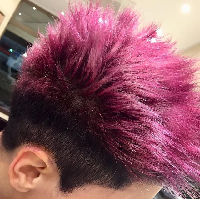Vista laterale di capelli a punta tinti di magenta con radici scure in un salone di bellezza.
