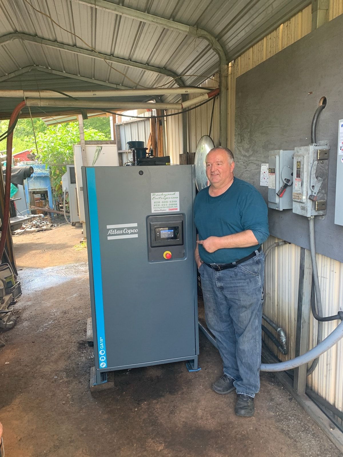 A man is standing in front of a machine in a garage.
