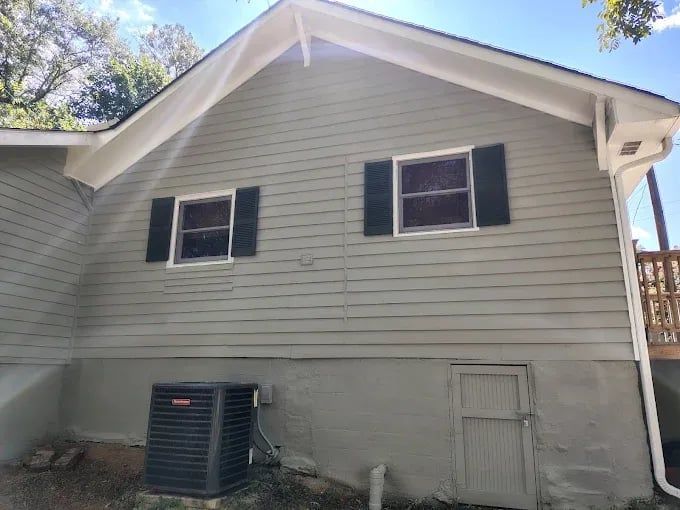 House exterior with light gray siding, black shutters, and a central air conditioning unit below the windows