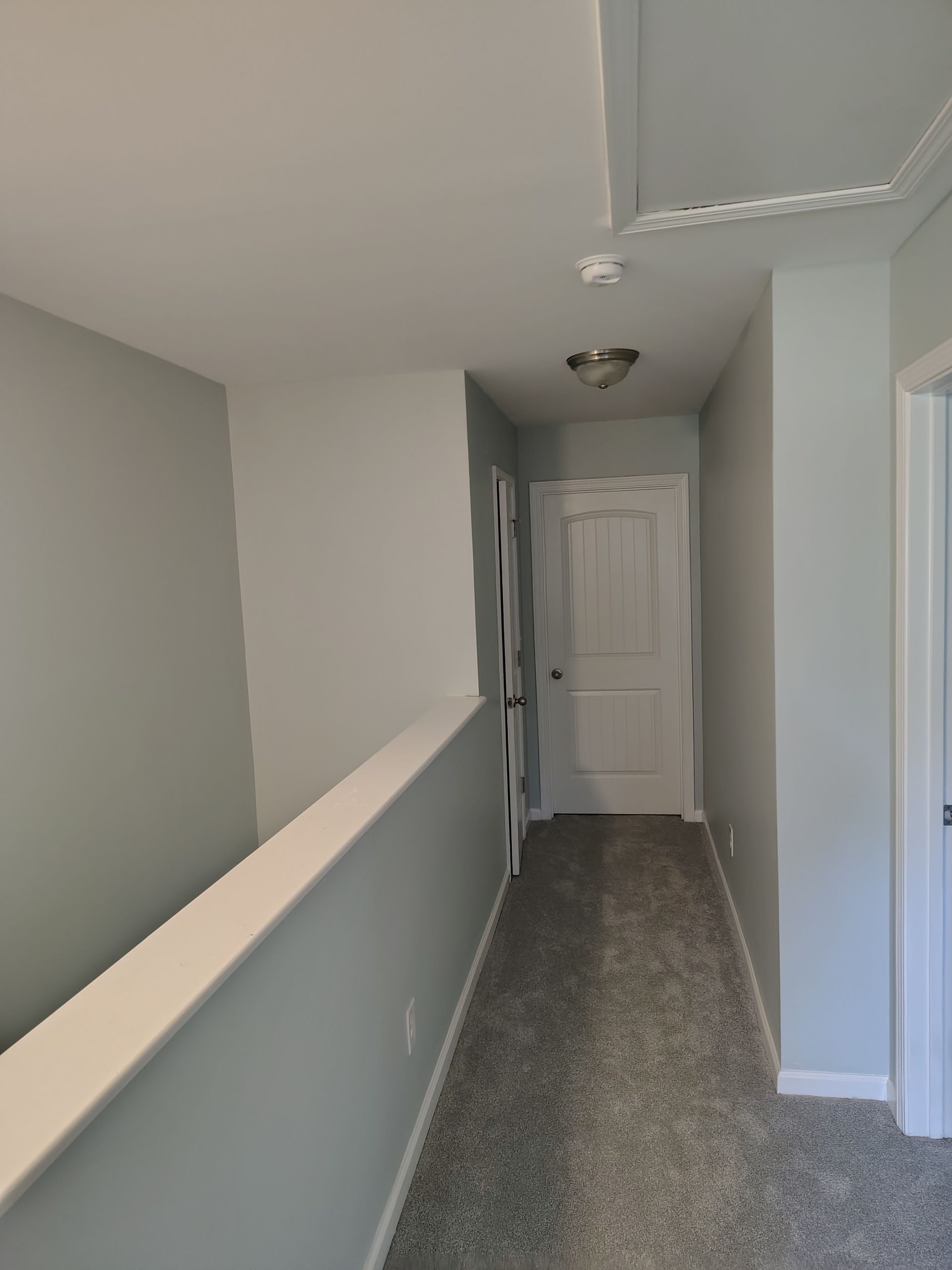 Empty upstairs hallway with gray walls, white trim, and closed white doors.