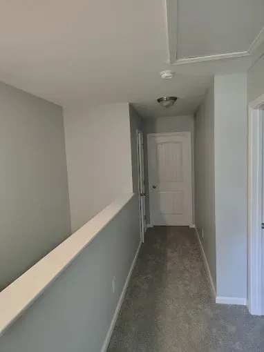Narrow hallway with gray walls, white trim, and a closed door at the end.
