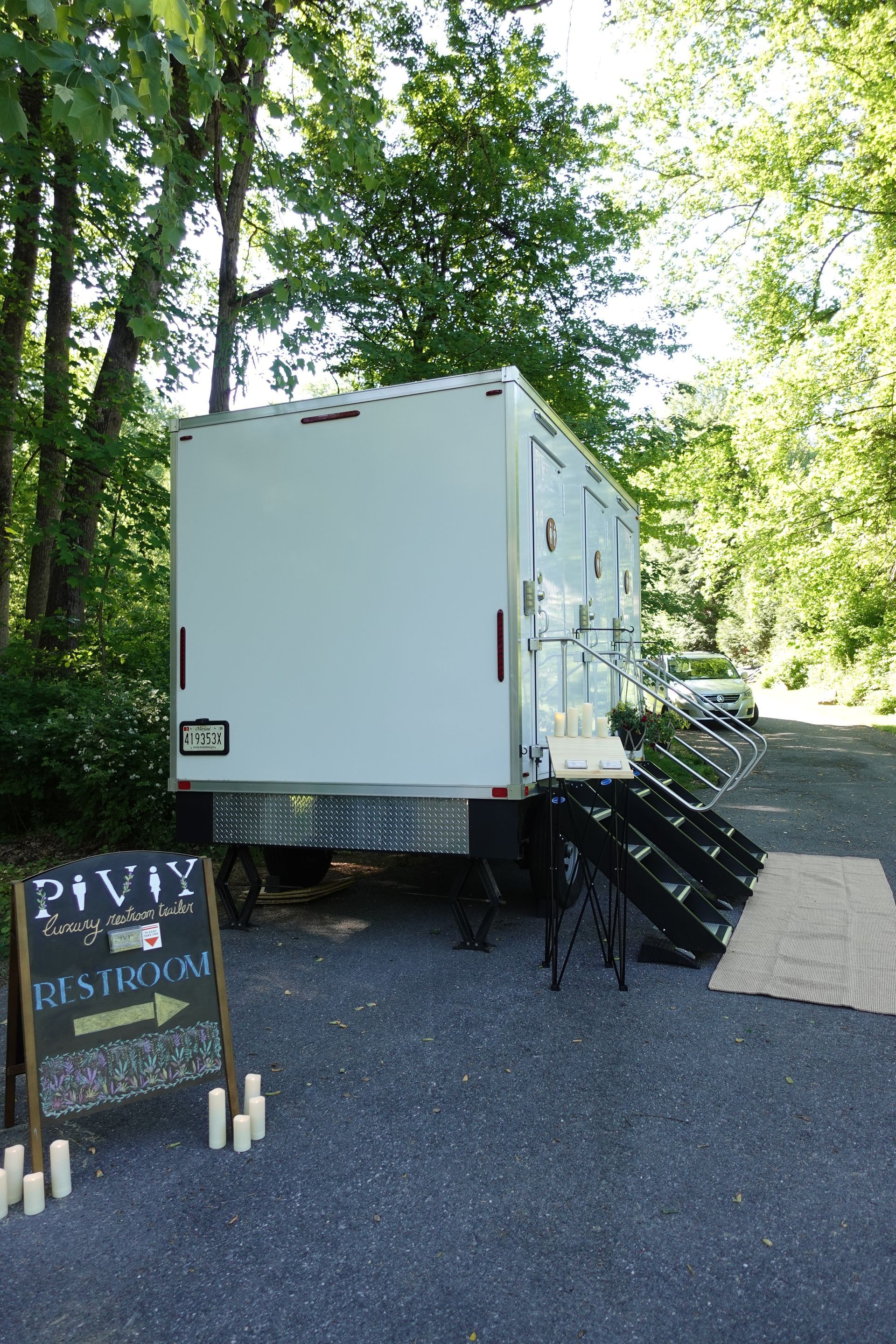 A white trailer is parked in a parking lot next to a sign.