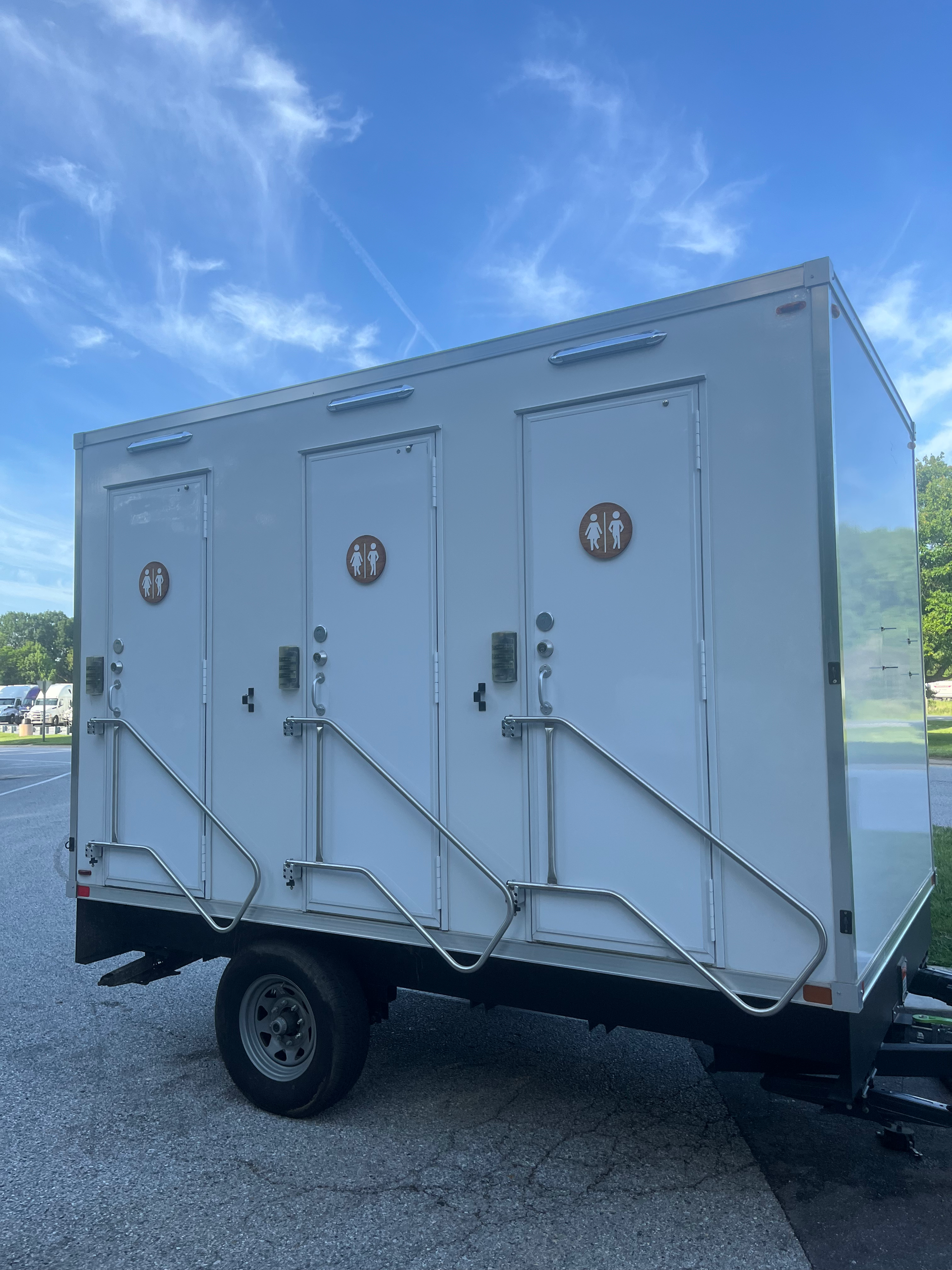 A white trailer with four doors is parked in a gravel lot.