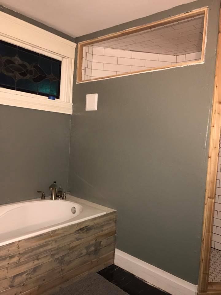 A bathroom with a bathtub and a window.