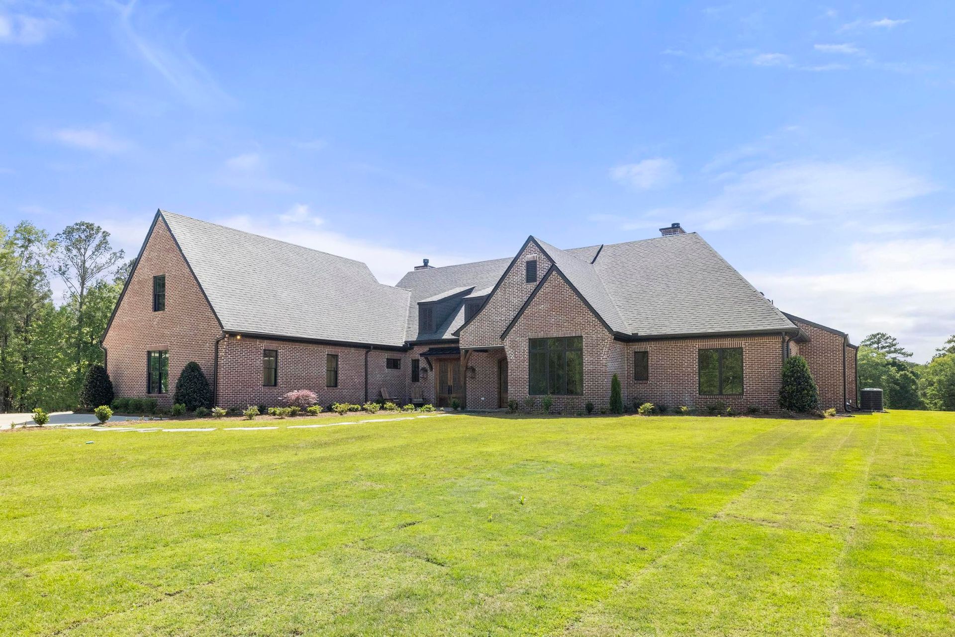 Stone house with a gray roof on a green lawn under a blue sky