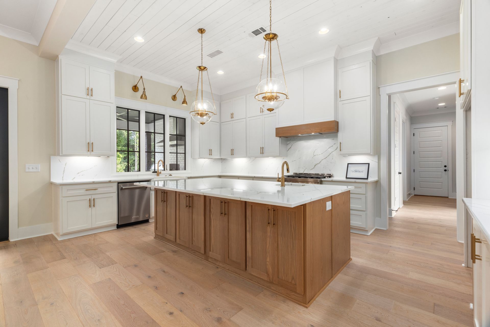 Bright white kitchen with a large wood island, pendant lights, and light wood floors