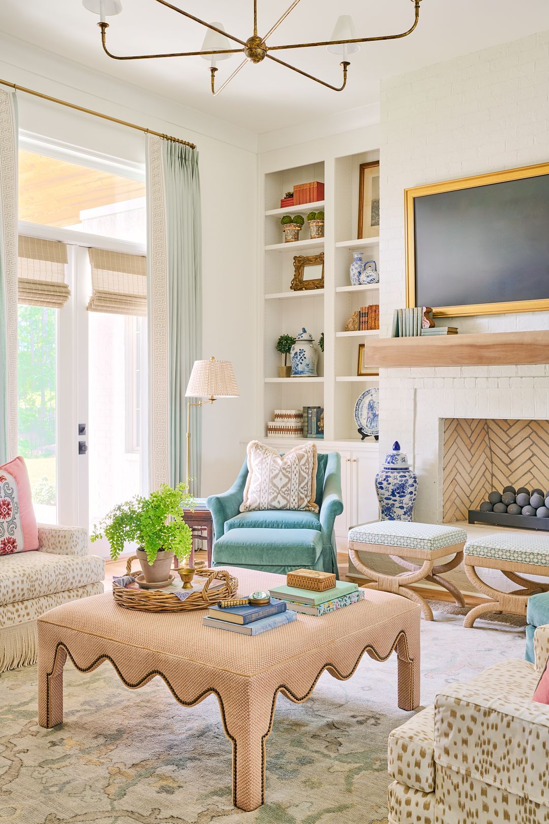Bright living room with teal chair, fireplace, built-in shelves, and a scalloped wood coffee table