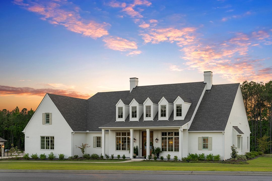 White suburban house with black roof at sunset under a pink-blue sky