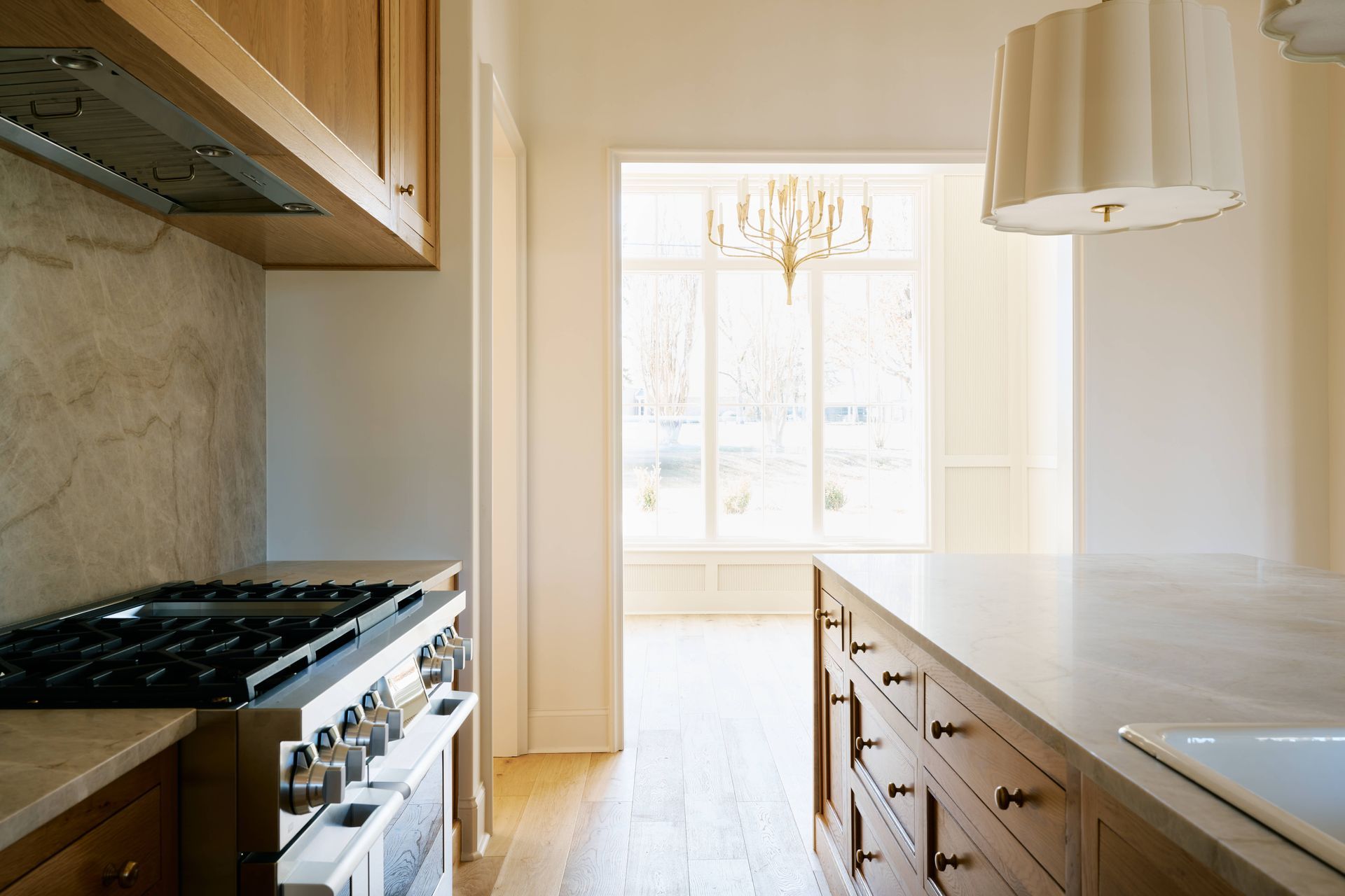 Bright, modern kitchen with a large island, gas stove, and sunlight through tall windows