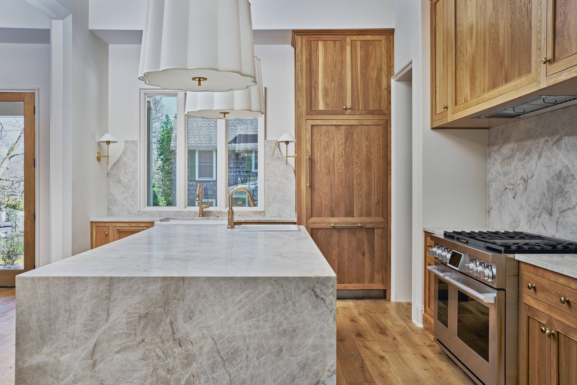 Modern kitchen with marble island, wood cabinets, and large window over a sink
