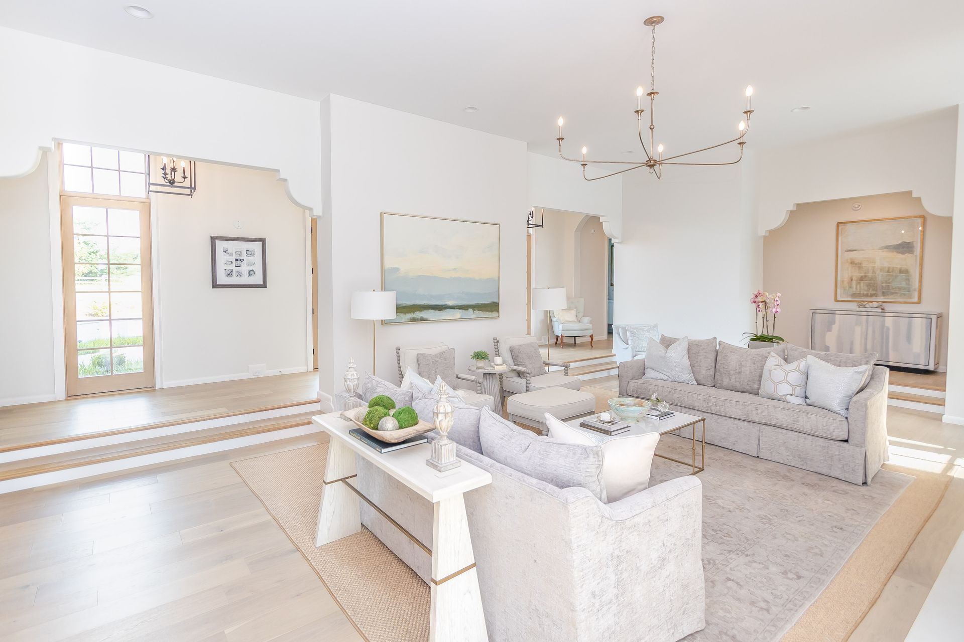 Bright, airy living room with white sofas, a coffee table, and large windows