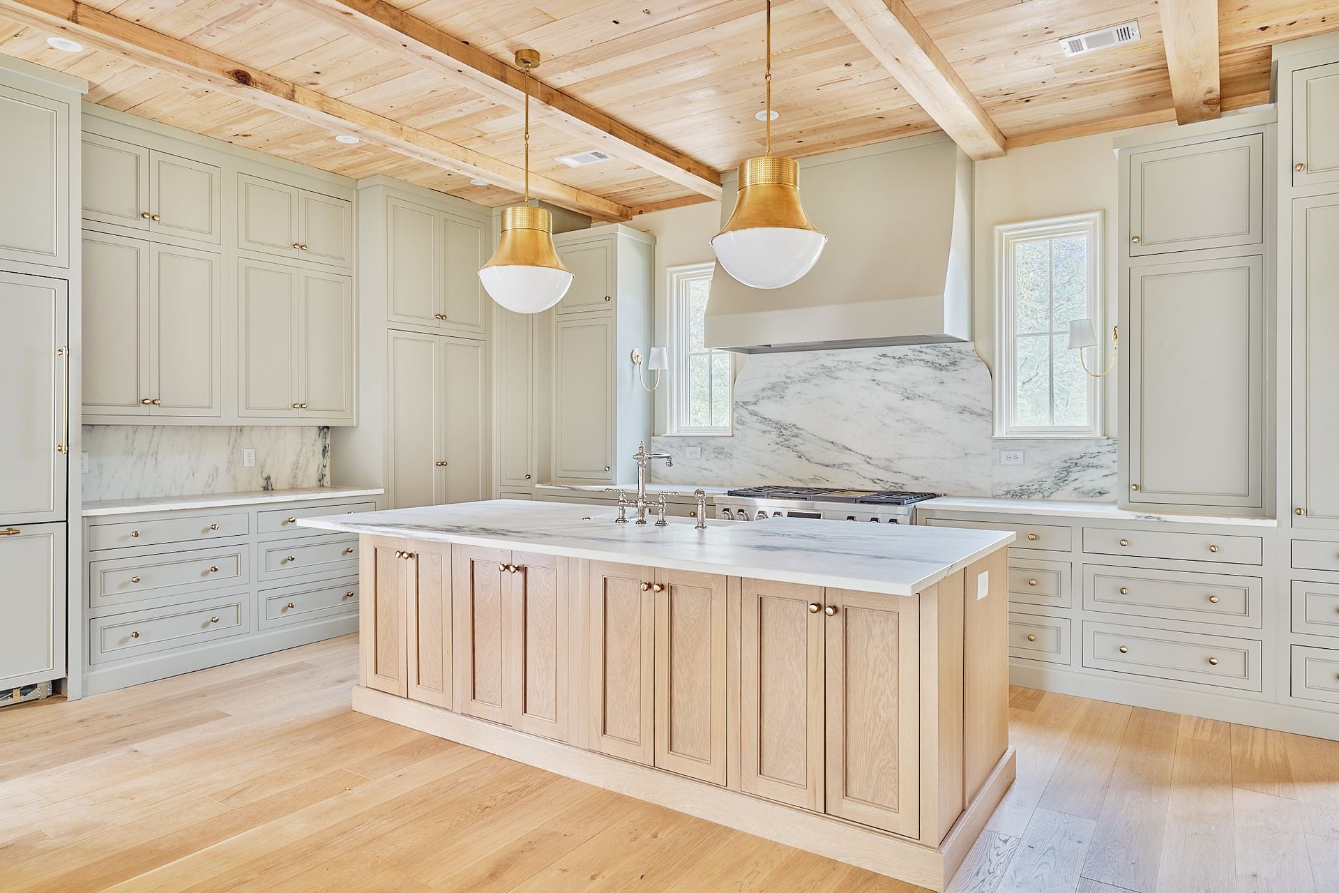 Bright modern kitchen with wood island, marble backsplash, white cabinets, and hanging pendant lights