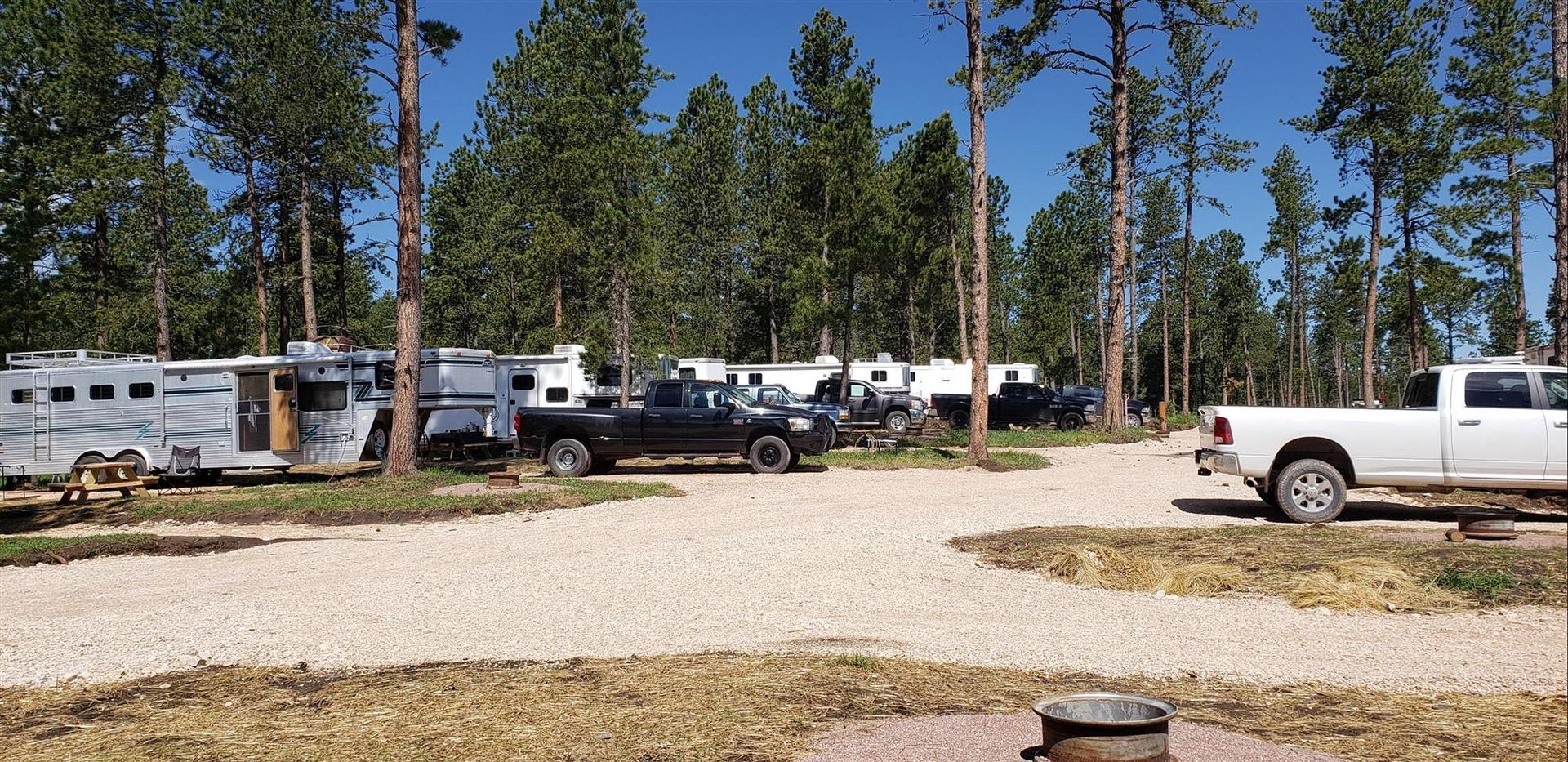 a white truck is parked in a gravel lot next to a trailer .
