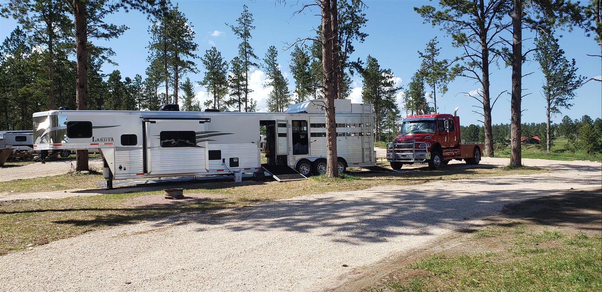 a rv is parked in a gravel lot next to a tow truck .