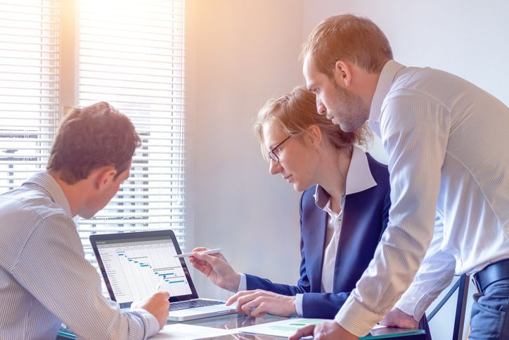 Image depicting business men and women looking at a computer graph of their progress