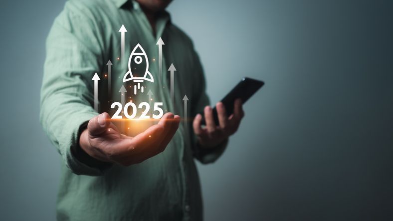 Man holding an image of a rocketship launching over the year 2025