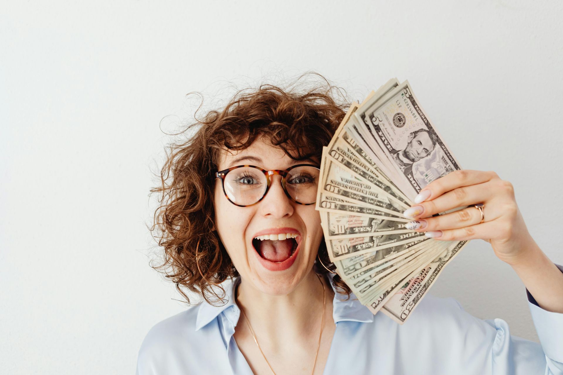 Woman with a happy facial expression displaying lots of cash