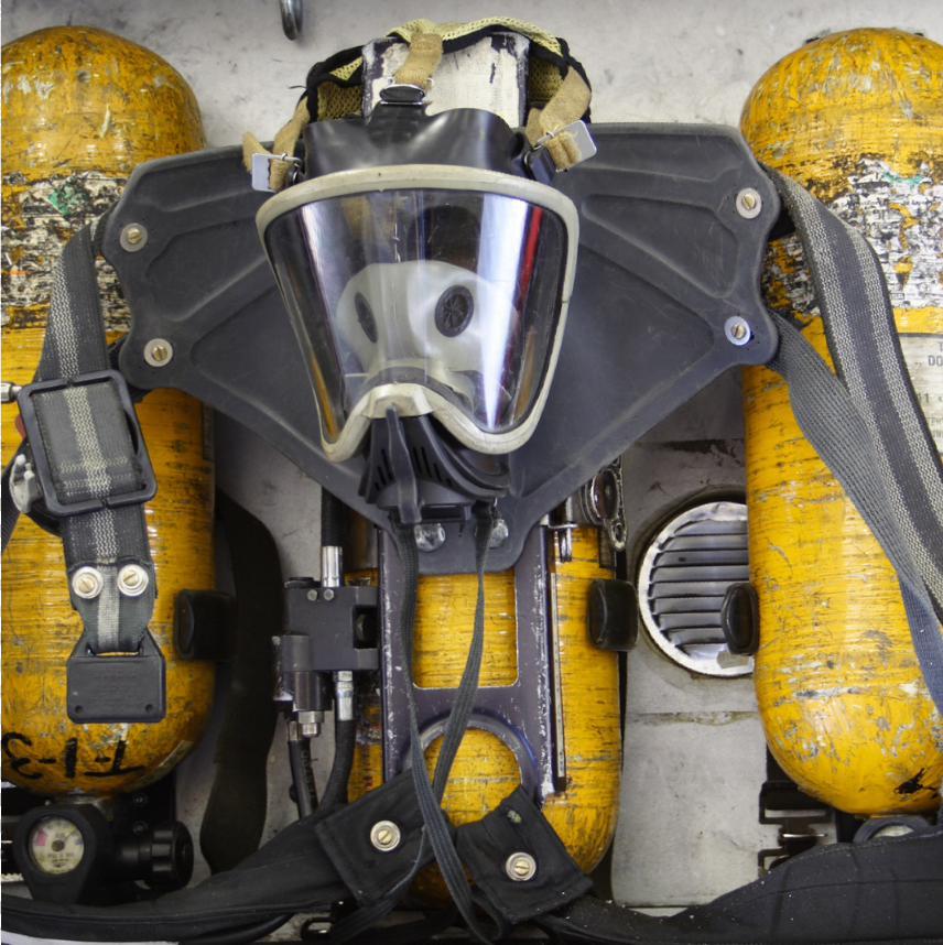 A gas mask is sitting on top of a yellow cylinder