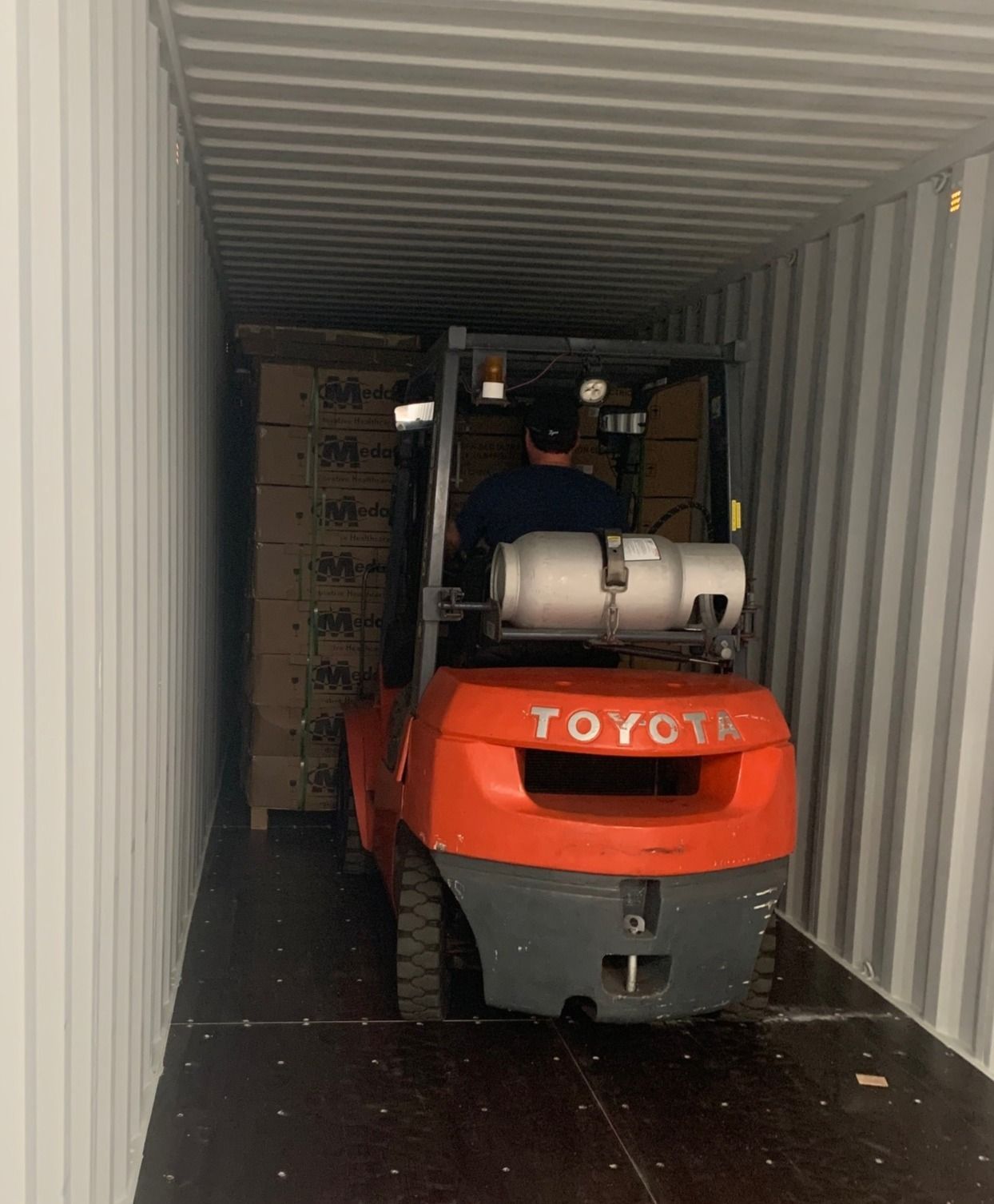 A man is driving a toyota forklift in a shipping container