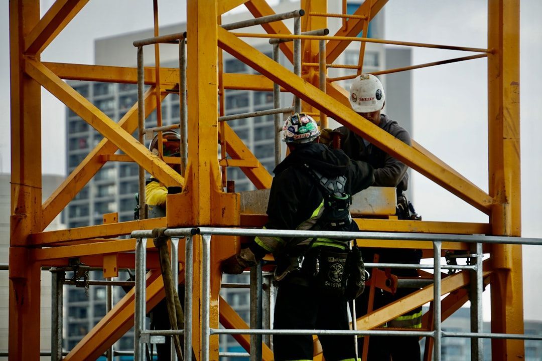 Two construction workers are working on a crane.
