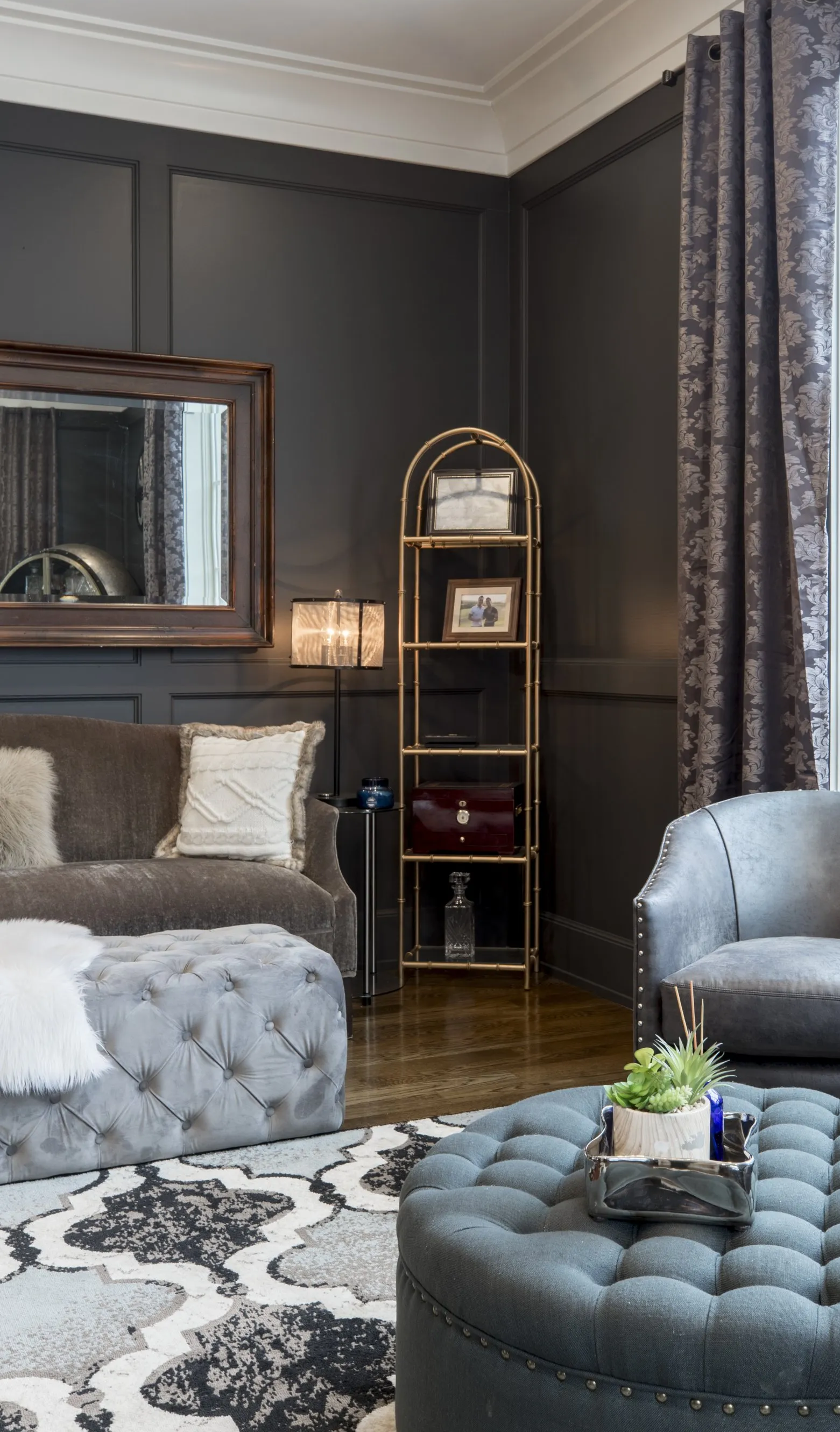 A living room with a couch , chairs , ottoman and a mirror