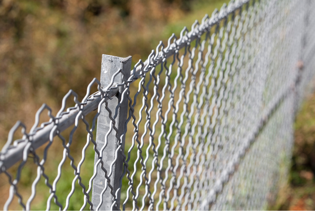 a close up of a chain link fence with a broken post